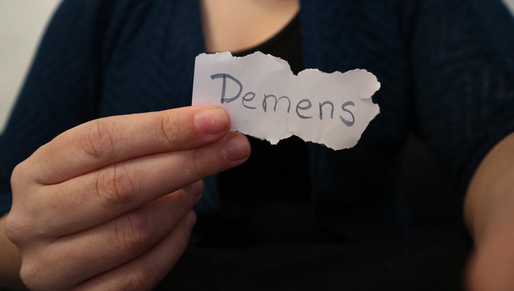 en hand håller upp en lapp där det står skrivet: demens