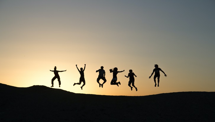 siluett av unga människor som hoppar glädjeskutt
