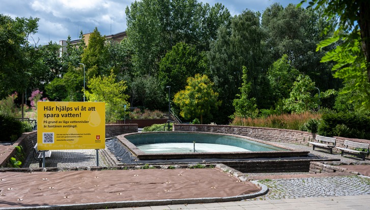 En gul skylt står mitt i en park.