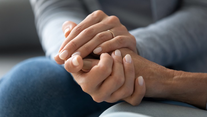 En äldre hand hålls i ett par yngre händer