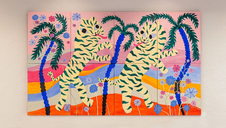 En färgglad målning föreställande två tigrar som står på bakbenen bredvid blåa palmer.