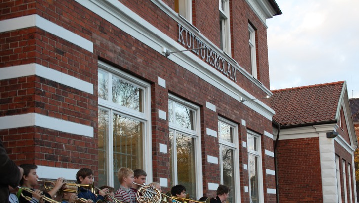 Elever från kulturskolan står framför skolan och spelar på sina blåsinstrument