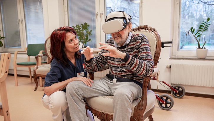Kvinnlig undersköterska hjälper boende med VR-upplevelsen
