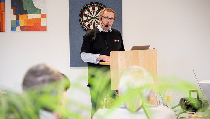 En man som står på ett podium framför en grupp människor.