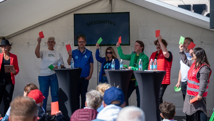 En grupp människor som står uppe på en scen och håller upp röda och gröna kort.