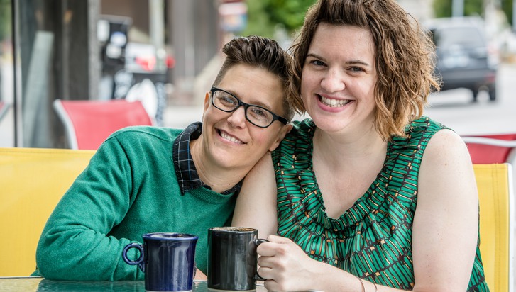 två kvinnor som sitter väldigt nära varandra på ett café utomhus