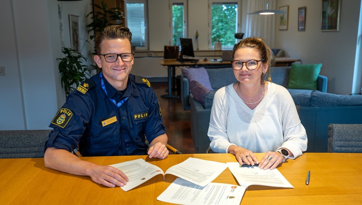 Polis i uniform sitter tillsammans med kvinna vid ett bord 