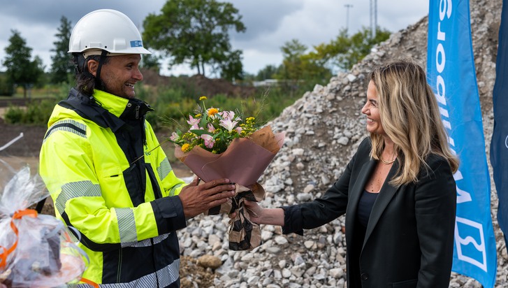 En kvinna ger blommor till en en man i varselkläder.