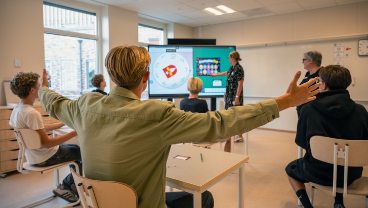 En grupp människor i ett rum med en stor skärm.