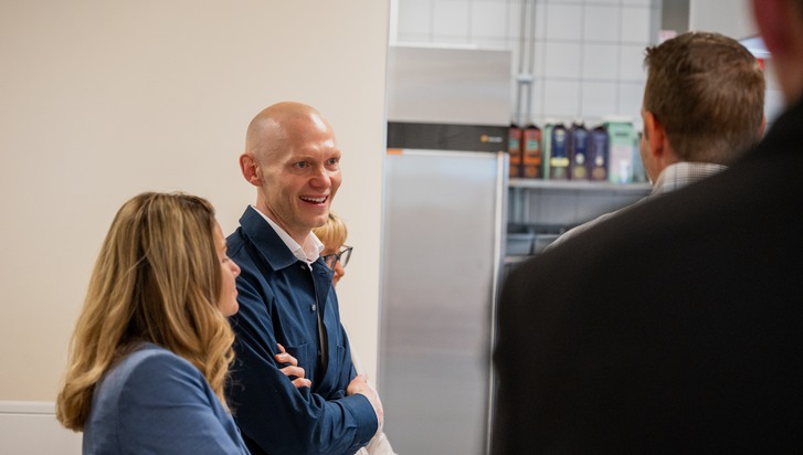 En grupp människor som står framför ett kök med ett kylskåp.