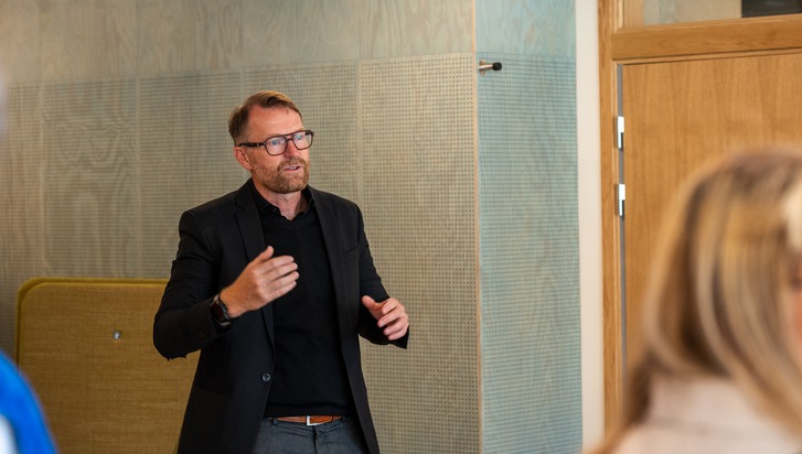 En man som står och pratar inför en grupp människor.