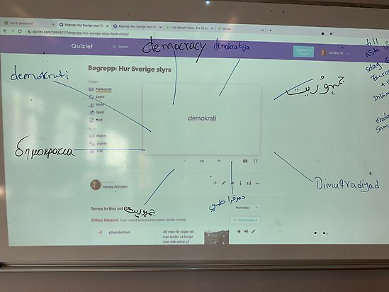 whiteboard med text som visar demokrati på olika språk